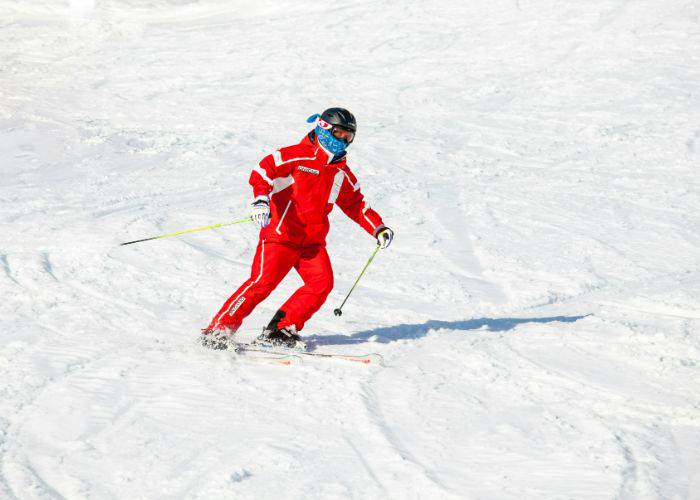 A skier in a bright red outfit swerving down the snowy slopes.